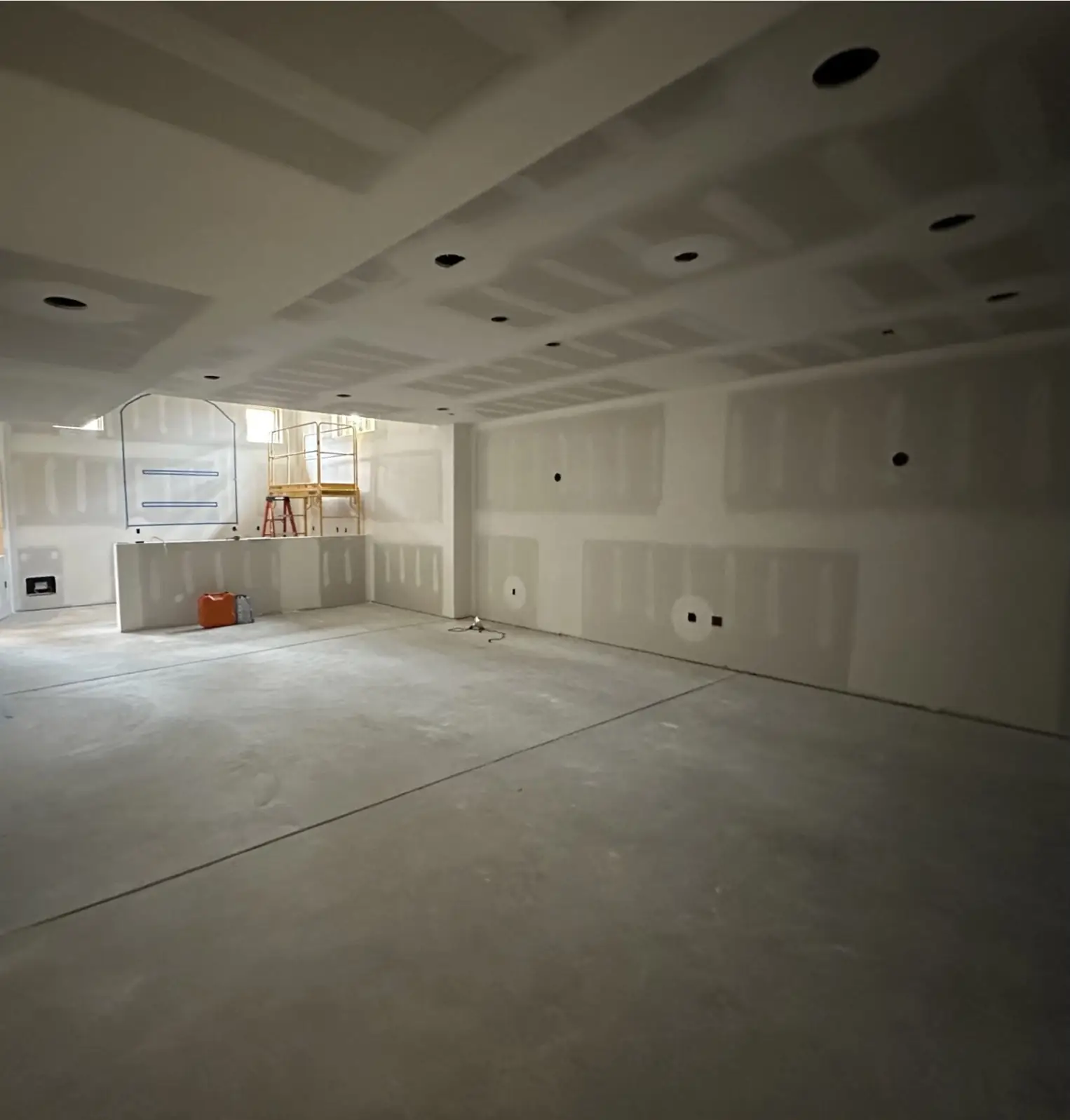 Main room before — bare drywall and a concrete floor