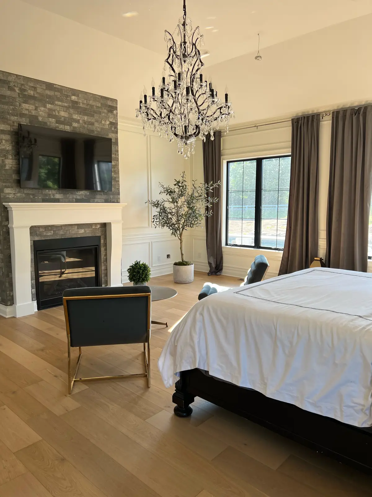 Primary bedroom fireplace with a white mantel and an olive tree — French-Inspired Residence