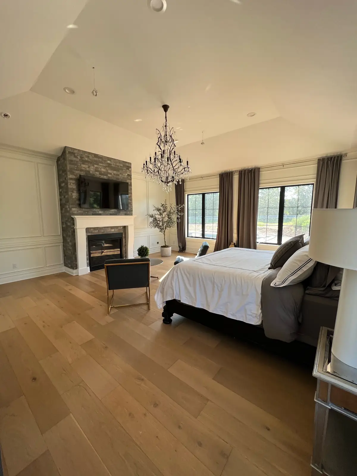 The primary bedroom beneath a tray ceiling, toward the fireplace and windows