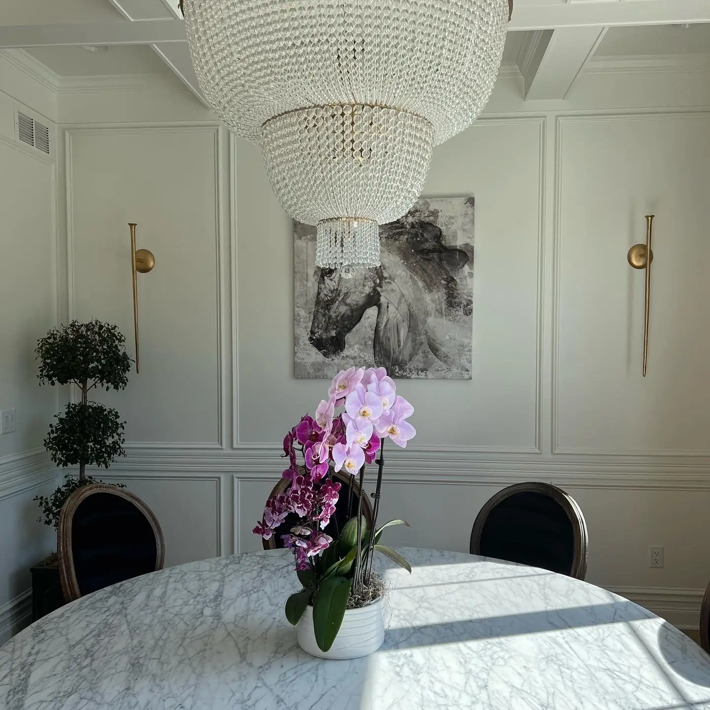 Dining room with paneled walls, gold sconces and framed art