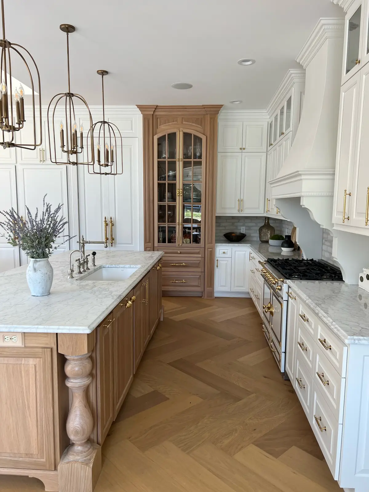 Glass-front cabinet at the end of the kitchen aisle — French-Inspired Residence