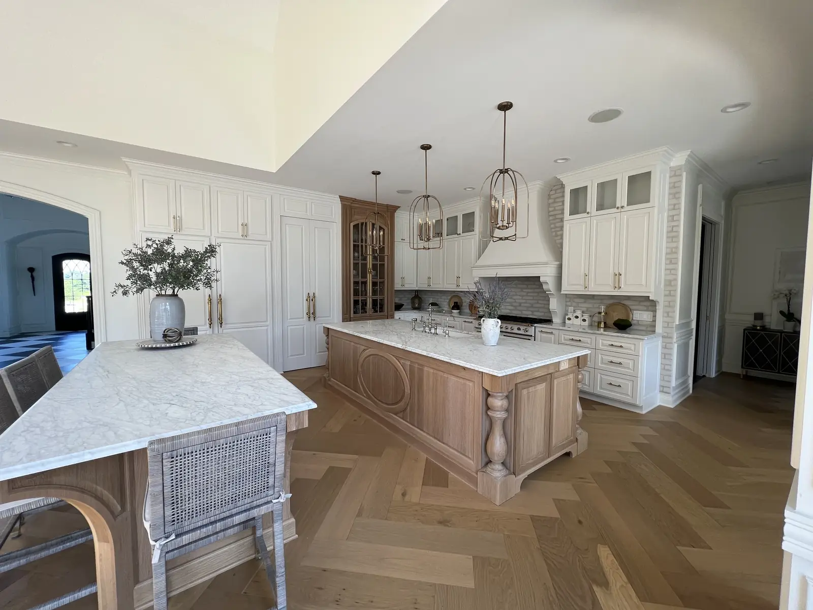 Two islands beneath brass lantern pendants — French-Inspired Residence