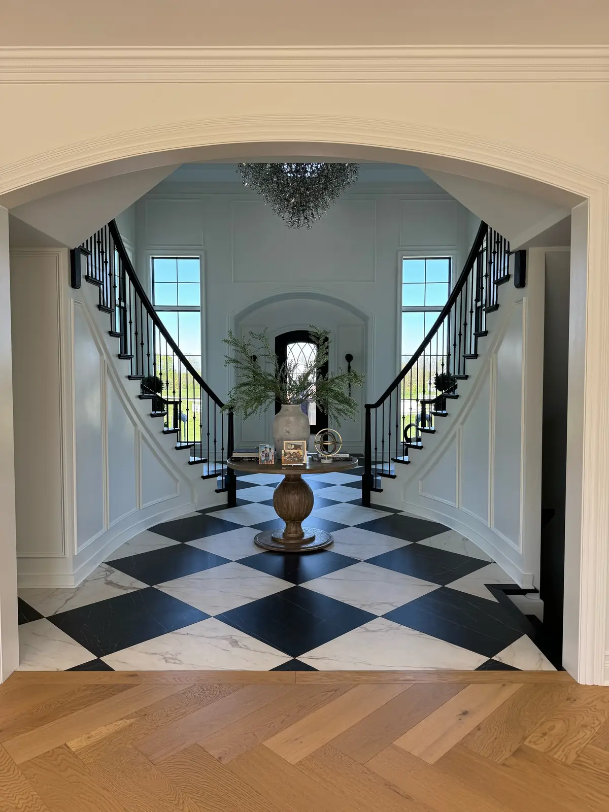 The foyer and double staircase seen through an arched opening