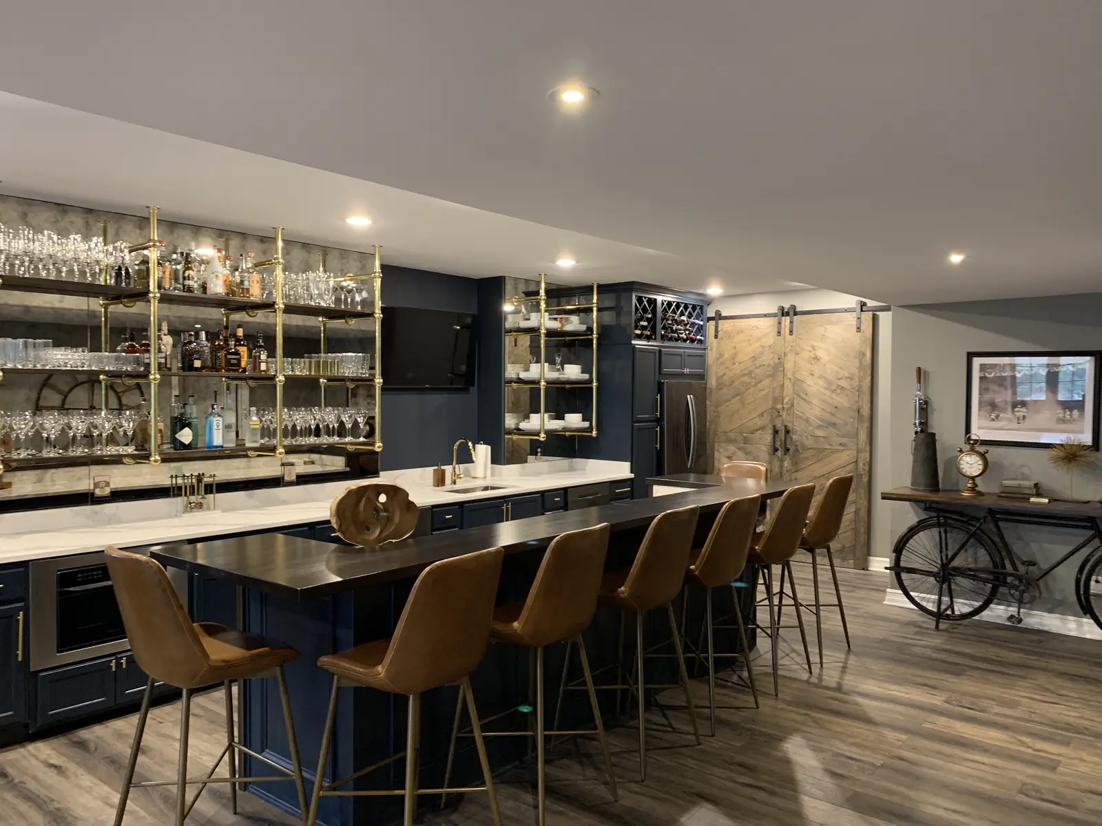Navy bar with brass shelving and leather stools — Indian Spring Project