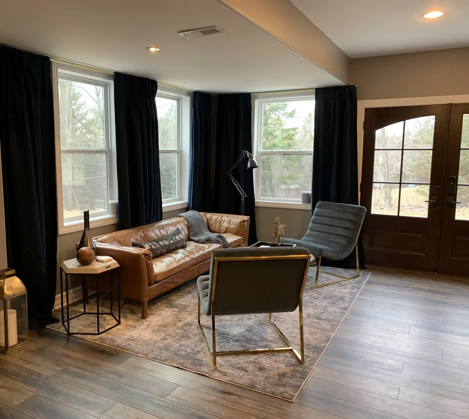 A seating nook by the windows, with a leather sofa and lounge chairs