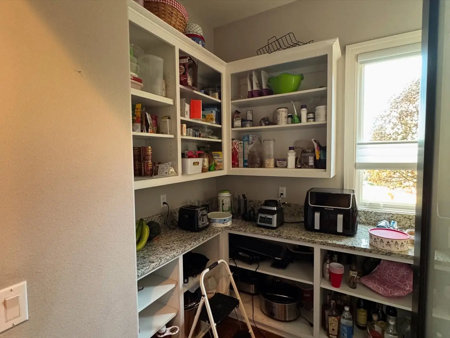 Pantry before — white shelving toward the window