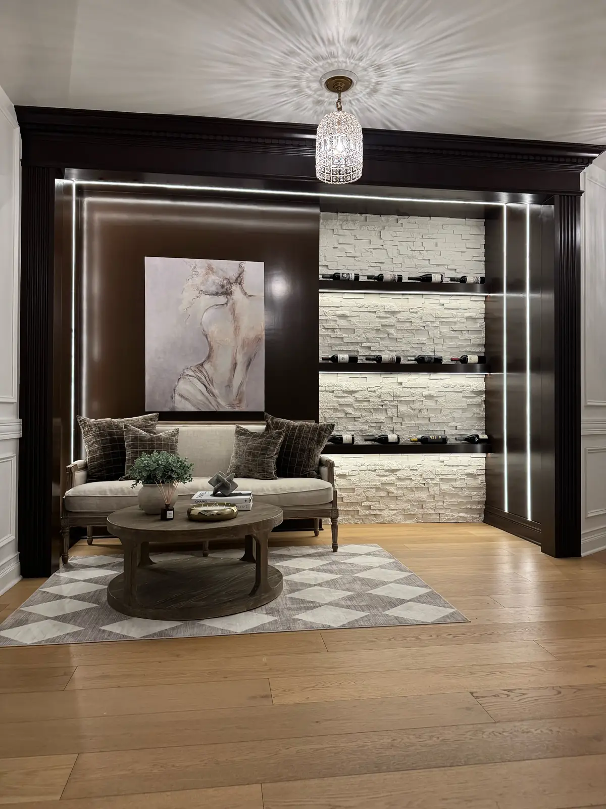 Wine lounge nook with a stacked-stone wine wall and crystal pendant