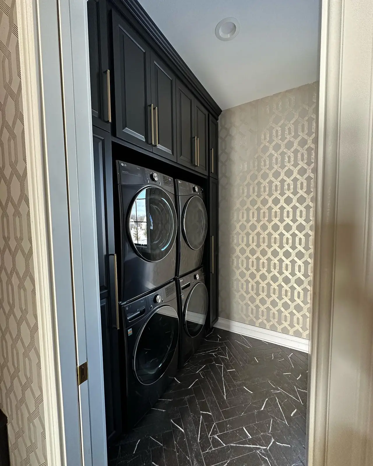 Laundry with dark cabinetry and patterned wallpaper — French-Inspired Residence